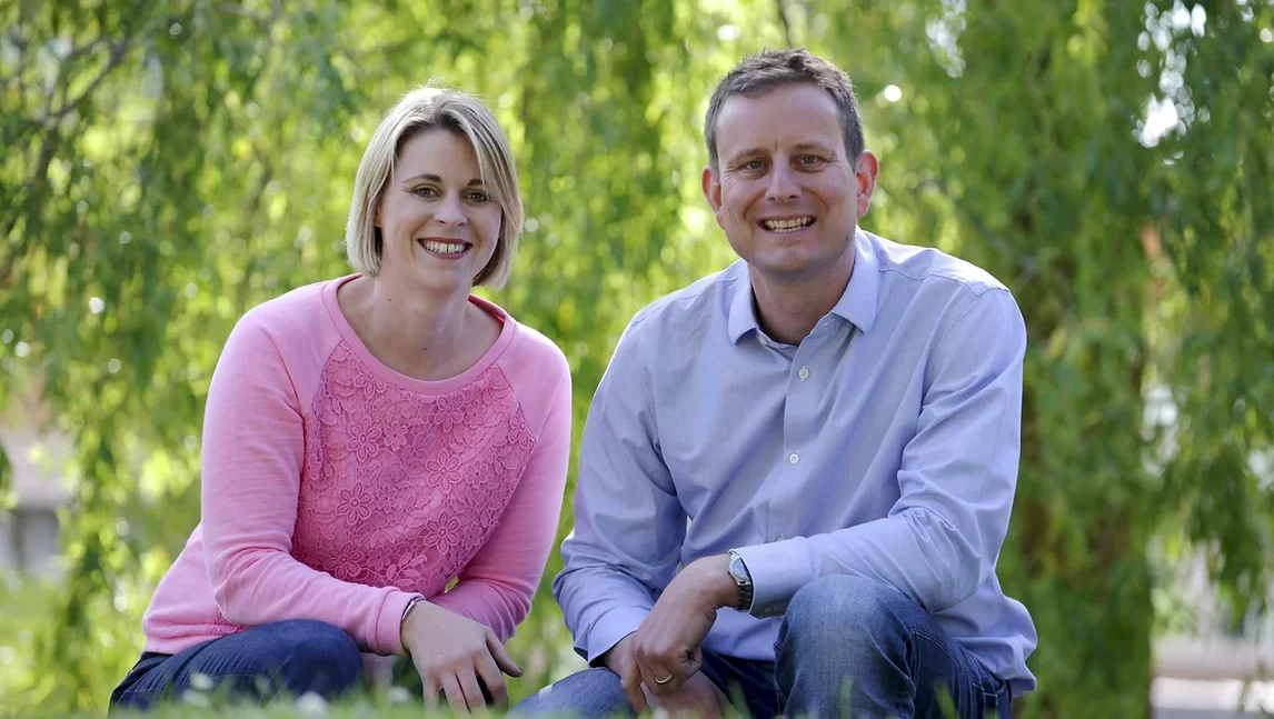 Nicola Chilman and Tom Minor, the founders of DoodleLearning, kneeling and smiling in front of a tree