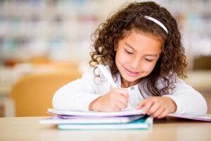 little girl working on math homework in the classroom