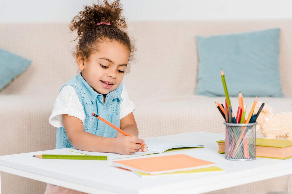 little girl drawing or working on homework in her living room