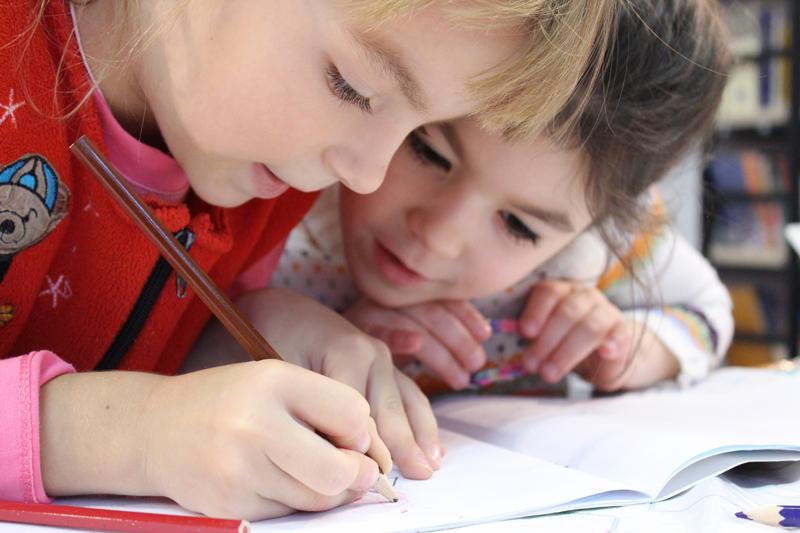 Two young children drawing shapes
