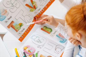 Girl coloring in letters of the alphabet