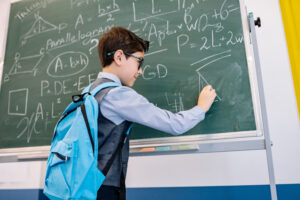 Student solving math problems on blackboard