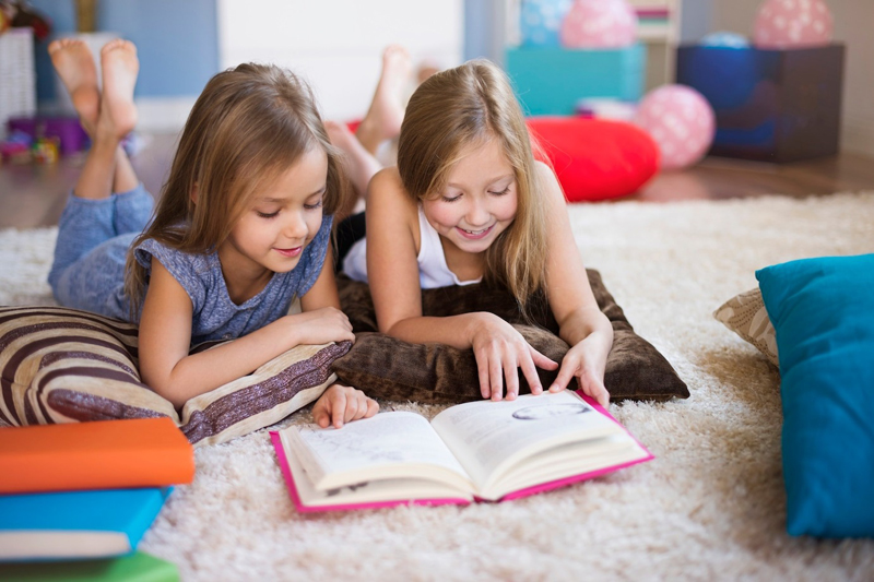 Two girls reading book together