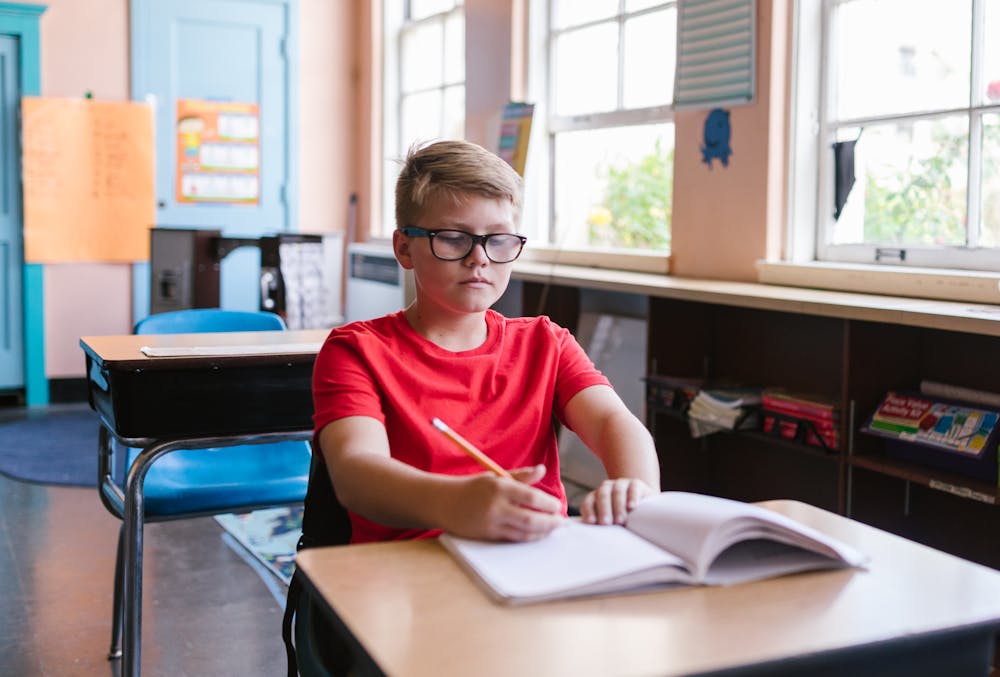 Boy writing in notebook in classroom